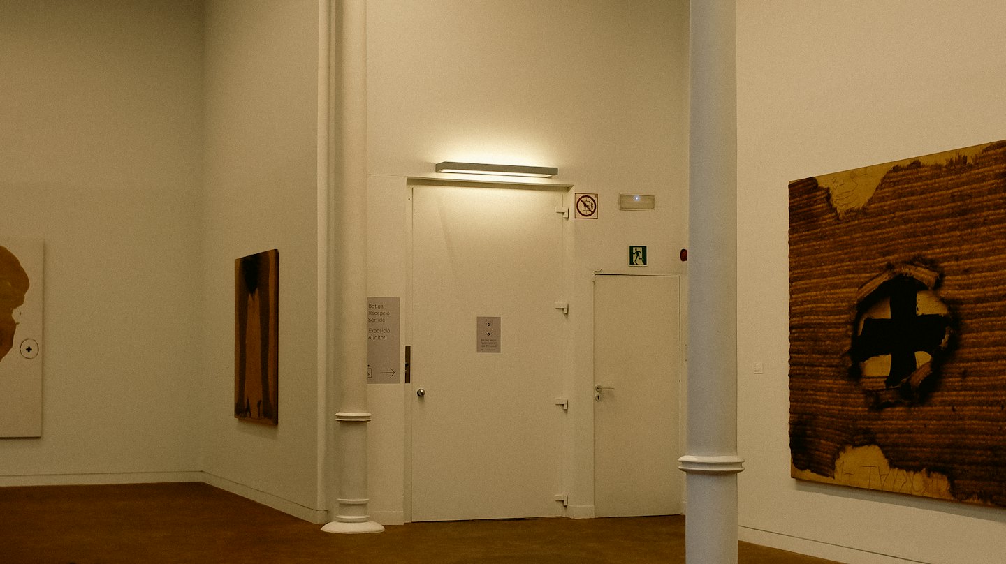 Drei abstrakte Gemälde, die an den weißen Wänden einer Galerie ausgestellt sind.
