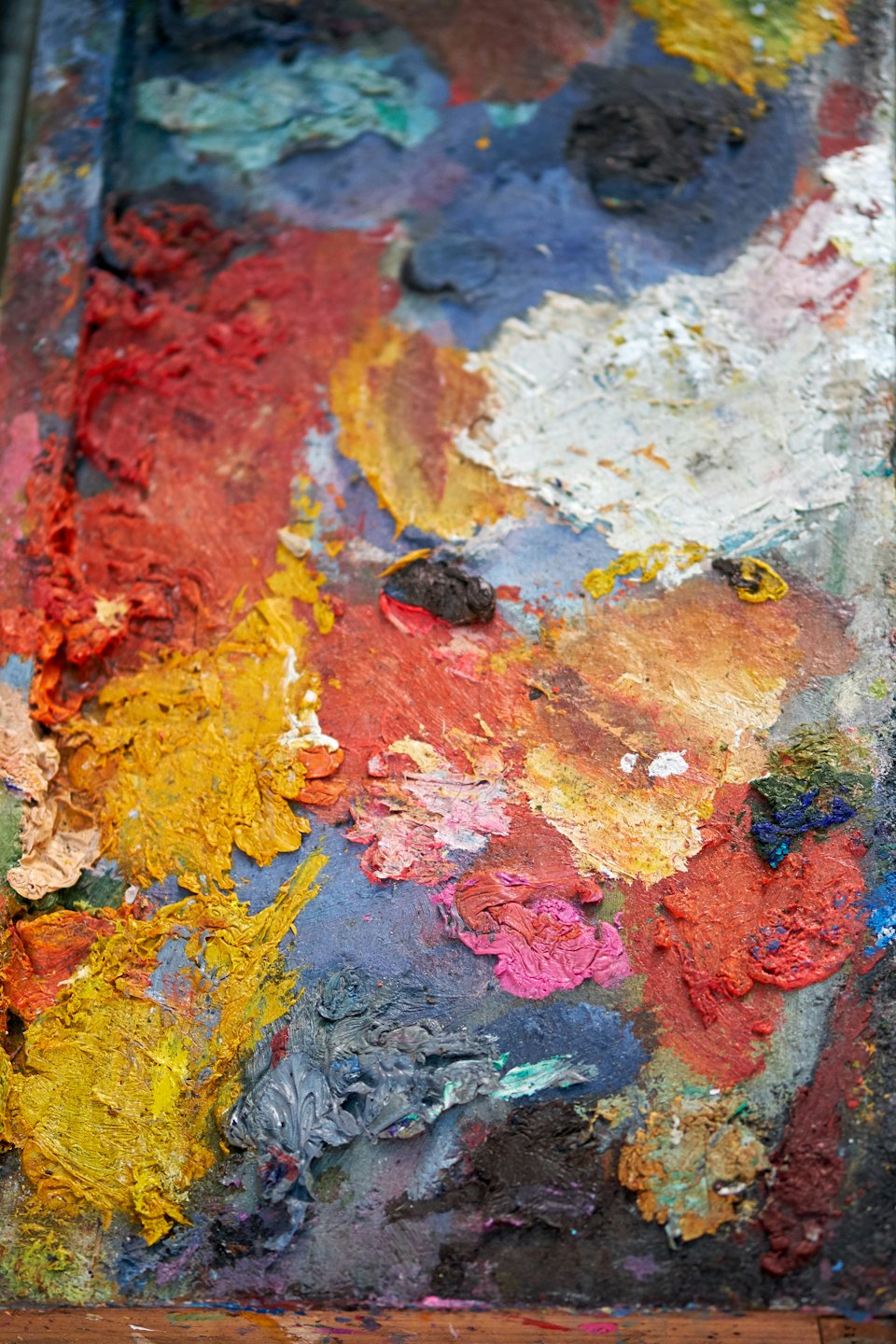 Künstlerpalette mit dicken, texturierten Ölfarben in verschiedenen Farben.